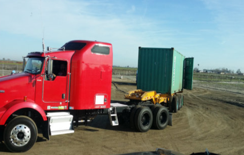 A red truck with a green container on the back.